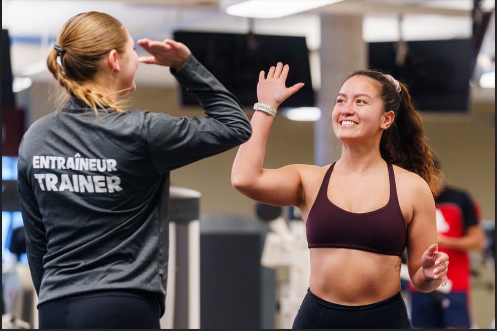 Une entraîneuse et une étudiante se font face dans une salle de sport